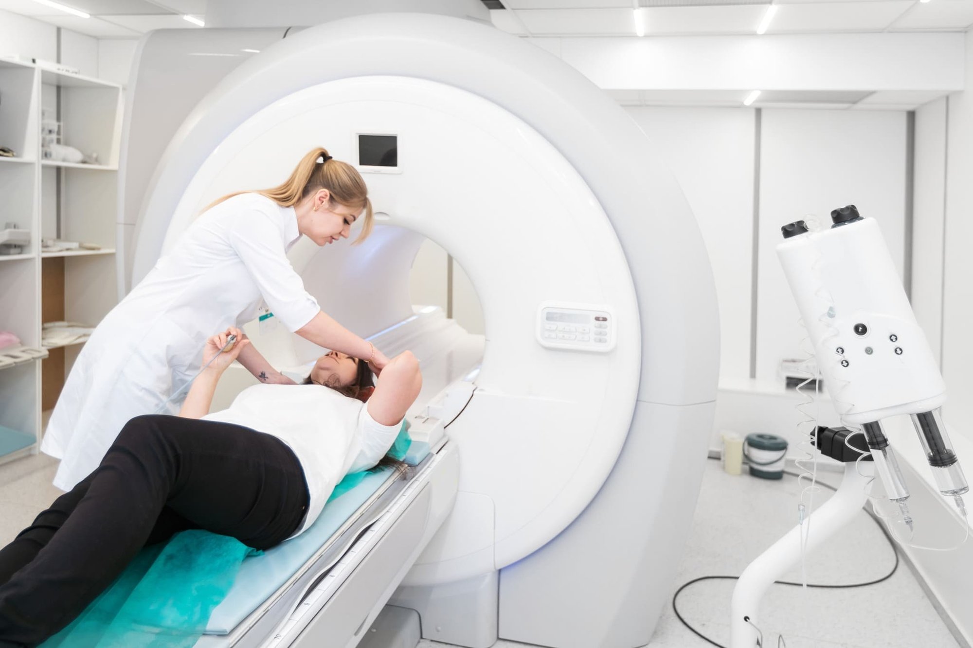 Ärztin positioniert auf dem Rücken liegende Patientin vor dem CT