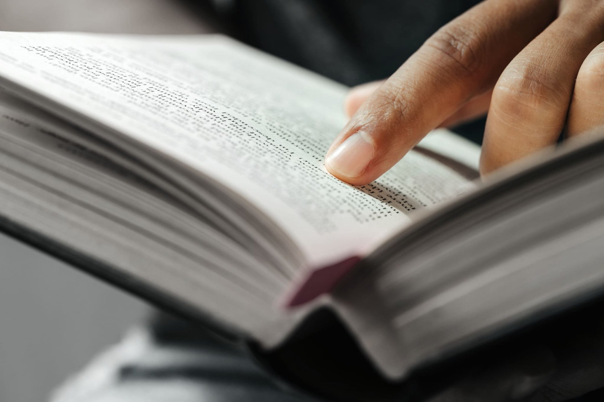 Person sucht etwas in einem aufgeschlagenen Buch